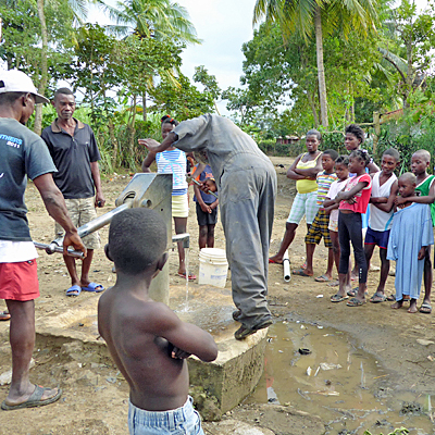 Villagers helping with pump repair, children watching