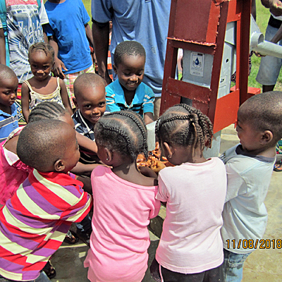 Children around the new pump enjoying safe water!