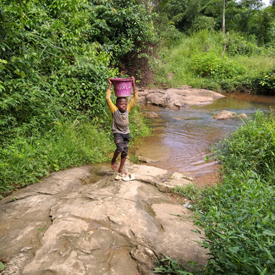Child drawing water from creek