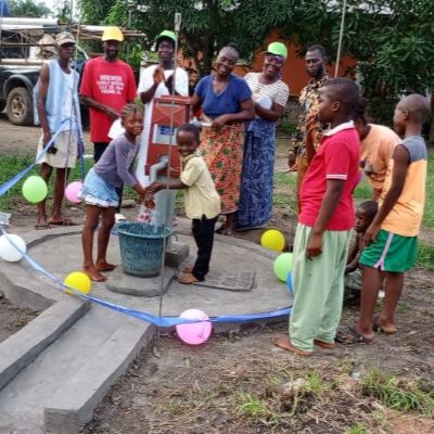 Happy villagers alongside their communal well 