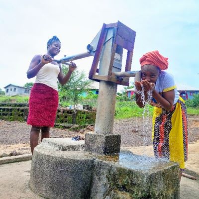 Villager enjoying clean drinking water after pump repairs 