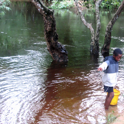 Child drawing drinking water from flooded river