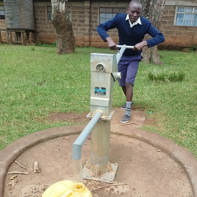 A students draws water from a pump after a successful repair 